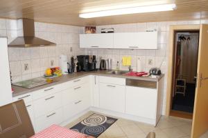 een keuken met witte kasten en een wastafel bij Haya in Naters