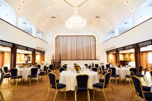 a banquet hall with tables and chairs and a chandelier at Hotel Cap Polonio in Pinneberg