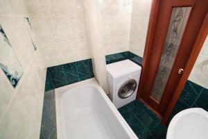 a bathroom with a tub and a washing machine at Modus Apartment in Tobolsk