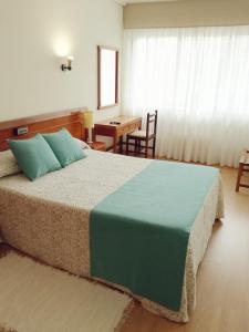 ein Schlafzimmer mit einem großen Bett und einem Tisch in der Unterkunft Hotel Almendra in Ferrol