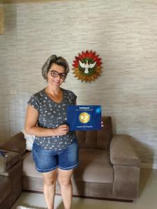 a woman standing in front of a couch holding a box at Casinha do Trapiche in Penha