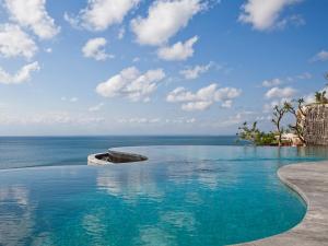 a swimming pool with a view of the ocean at Anantara Uluwatu Bali Resort in Uluwatu