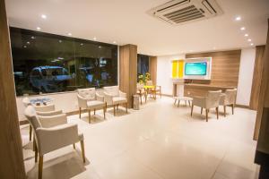 a dining room with tables and chairs and a television at Barravento Praia Hotel in Ilhéus