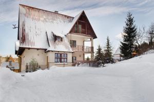 una casa con nieve en el suelo delante de ella en Willa Miś, en Krynica-Zdrój