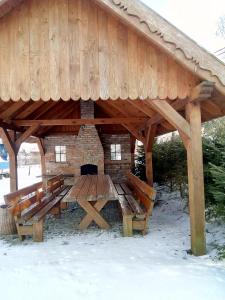a wooden pavilion with benches and a fireplace at Apartament ogrodowy in Rydzewo +10 photos