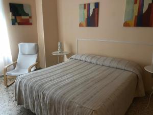 1 dormitorio con 1 cama y 1 silla blanca en B&B Sansevero Naples, en Nápoles