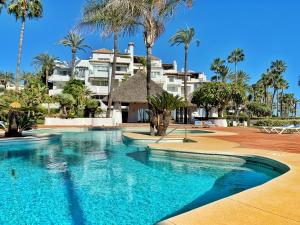 einen Pool vor einem Hotel mit Palmen in der Unterkunft Alcazaba Beach Apartment 3302 in Estepona