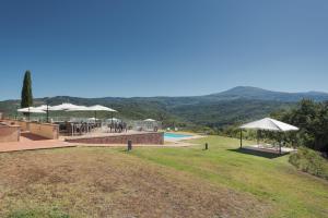 un complejo con piscina, mesas y sombrillas en Agriturismo Villa La Palazzetta Terre di GIORGIO en Castiglione dʼOrcia