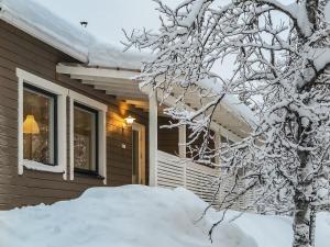 a house covered in snow next to a tree at Holiday Home Hilla b by Interhome in Saariselka