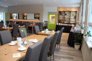 una sala da pranzo con tavoli e sedie in legno di Hotel Bannewitz B&B a Bannewitz