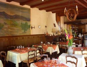 a restaurant with tables and chairs and a painting on the wall at Hôtel des Vosges 5 rue de la gare in Obernai