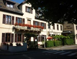 a white building with red flowers on a balcony at Hôtel des Vosges 5 rue de la gare in Obernai