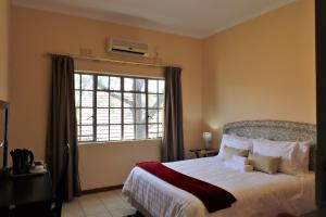 ein Schlafzimmer mit einem Bett und einem großen Fenster in der Unterkunft Sentosa Guest House in Francistown