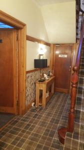 Habitación con escritorio, TV y puerta. en Ivanhoe Guest House en Inverness