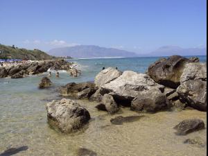 einen Strand mit Felsen und Menschen im Wasser in der Unterkunft Short Lets Vacanze "Massimo" in Trappeto