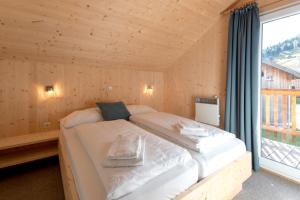 Cama en habitación de madera con ventana grande en Hirsch Chalet en Sankt Lorenzen ob Murau