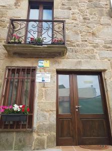 a building with a door and a balcony and flowers at Albergue A Salazon in Villanueva de Arosa