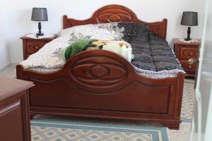 sypialnia z drewnianym łóżkiem i 2 szafkami nocnymi w obiekcie City Apartment sur le port de Mahdia Free Wifi w mieście Mahdia