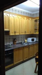 eine Küche mit Holzschränken, einer Spüle und einer Mikrowelle in der Unterkunft Casa Nicolás in Avila