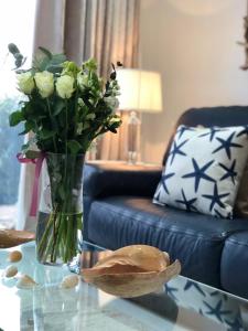 un jarrón de flores sobre una mesa en la sala de estar en Ocean Drive Deluxe Apartment ground floor Brean Down complimentary Tray and continental Breakfast, en Brean