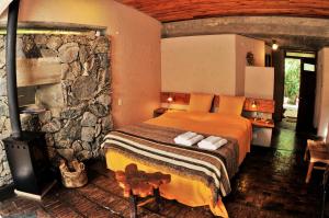 1 dormitorio con cama y pared de piedra en Cuatrovientos Hostería en San Javier