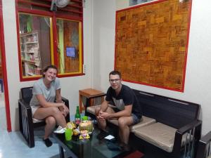 a man and a woman sitting on a couch with a table at Gonias Hostel in Gunungsitoli