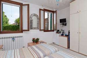 a bedroom with a bed and two windows and a kitchen at Ca' Del Pomo Grana' Al Roman in Murano