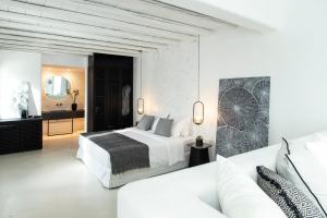 a white bedroom with a bed and a couch at Nimbus Mykonos in Agios Stefanos