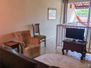 a living room with a tv and a chair at Seo Chico Sobradinho in São Sebastião