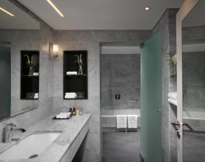 a bathroom with a tub, sink and mirror at The Inbal Jerusalem in Jerusalem