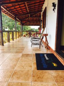 a porch with a bench and a rug on the floor at Pousada São Gonçalo in São Gonçalo do Rio das Pedras
