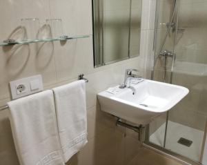 ein Badezimmer mit Waschbecken, Dusche und Handtüchern. in der Unterkunft Hotel Almendra in Ferrol