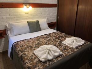 1 dormitorio con 1 cama con 2 toallas en Tinajas del Lago Bungalows Apart en Villa Carlos Paz