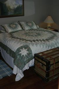 a bedroom with a bed with a blanket and a trunk at Prairie Creek Inn in Walton