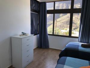 une chambre avec deux lits et une commode et une fenêtre dans l'établissement Apartamentos Acorán Mogán, à Mogán