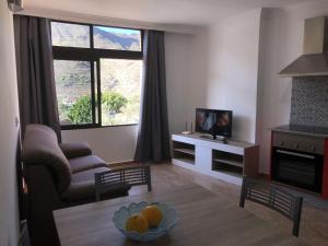 a living room with a couch and a tv and a table at Apartamentos Acorán Mogán in Mogán