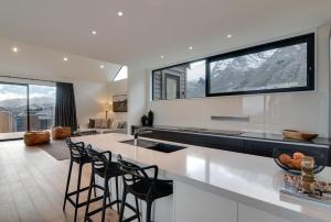 a kitchen with a white counter and stools at 4 Stockyard Lane in Queenstown