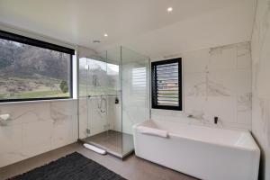 a white bathroom with a tub and a glass shower at 4 Stockyard Lane in Queenstown