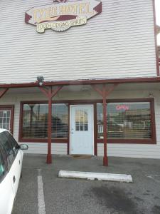 a store front with a white car parked in a parking lot at Tyee Restaurant and Motel in Coupeville