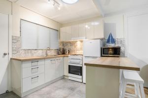 パーム・コーブにあるTropical Unit with Private Fenced Garden Close to The Beach 4のキッチン(白いキャビネット、白い電化製品付)