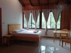 1 dormitorio con cama, mesa y ventanas en Hotel El Congo, en Drake