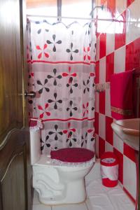 uma casa de banho com um WC com uma cortina de chuveiro vermelha e branca em Mindoxtrem Birds em Mindo