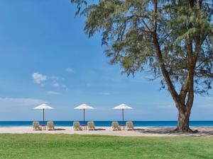 a group of chairs and umbrellas on a beach at Dusit Thani Laguna Phuket in Bang Tao Beach