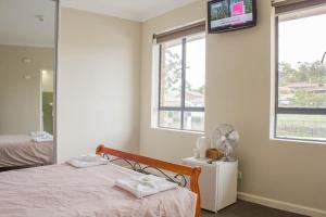 1 dormitorio con 1 cama y TV en la pared en Figtree Hotel Wollongong, en Wollongong