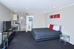 a bedroom with a bed and a kitchen with a sink at Livingston Motel in Whakatane