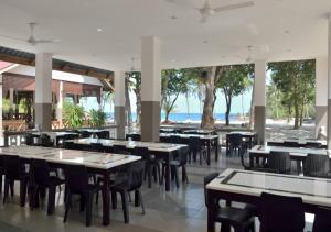 an empty restaurant with tables and chairs and the ocean at Delima Redang Resort in Redang Island