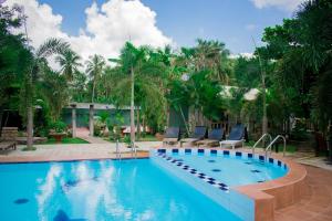 a swimming pool with chairs and palm trees at Tishan Holiday Resort in Polonnaruwa