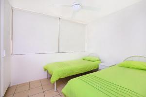 two beds in a room with green sheets at Eastbourne U4 80 Esplanade Golden Beach in Caloundra
