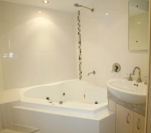 a white bathroom with a tub and a sink at Allamanda U2 Awesome Location in Caloundra