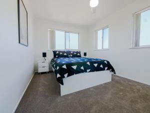 a white bedroom with a bed and two windows at Explorer Cove Unit 6 31 Kennedy Pde in Caloundra